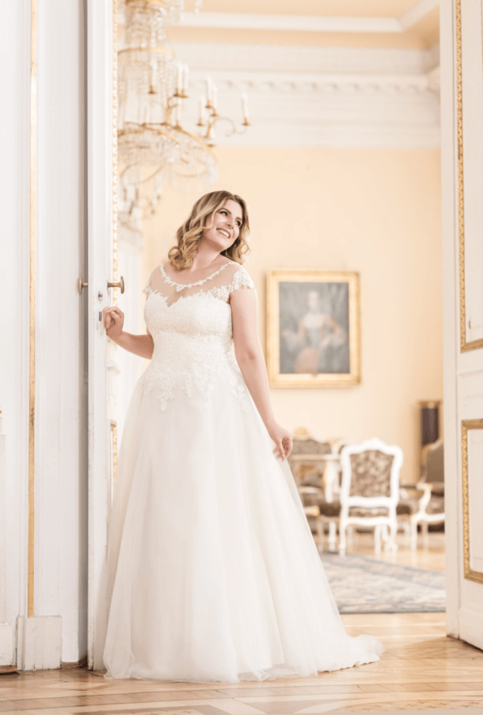 Eine Frau in einem weißen Brautkleid steht in einer Tür.