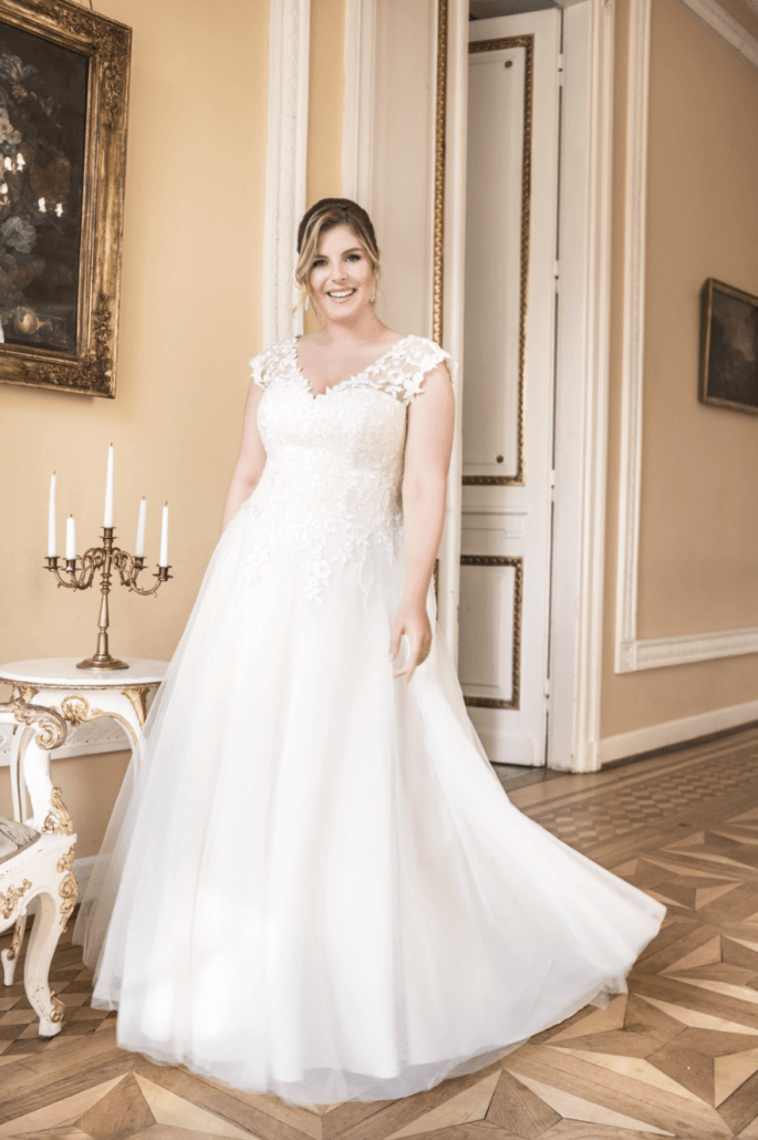 Eine Frau in einem weißen Brautkleid steht in einem Raum.