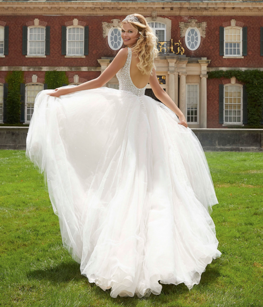 Eine Frau in einem Brautkleid steht vor einem Backsteingebäude.