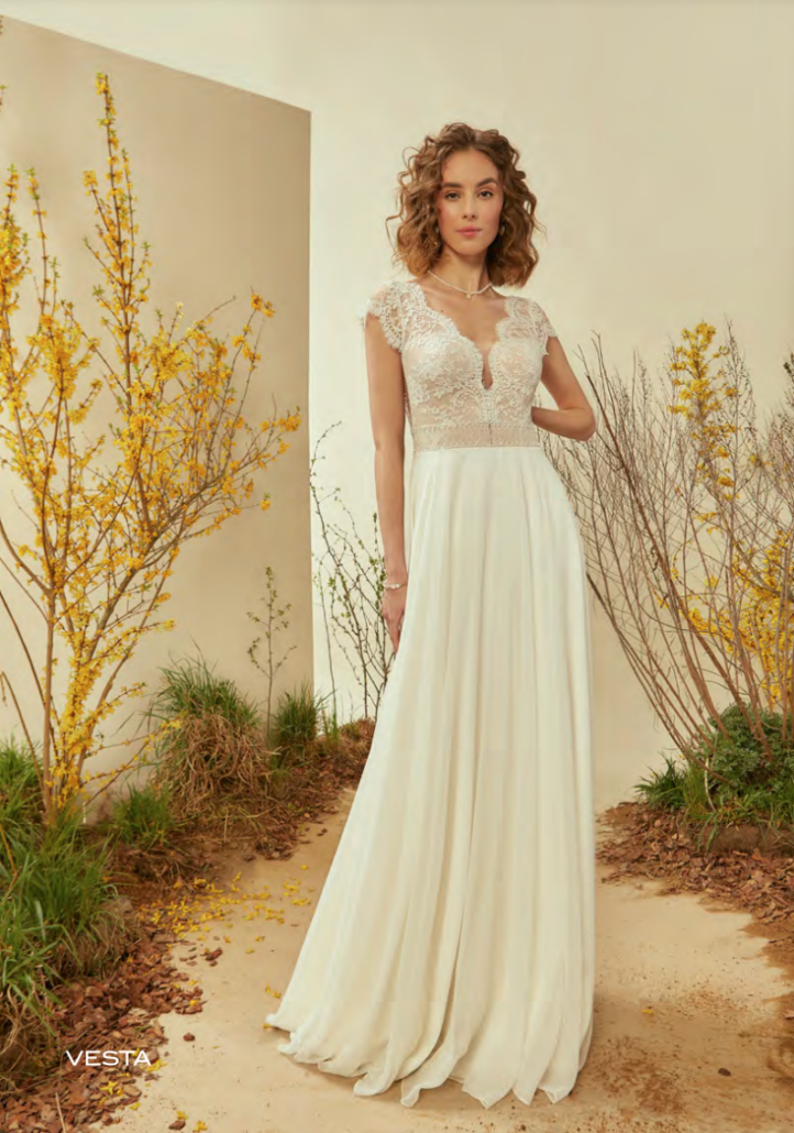 Eine Frau in einem weißen Hochzeitskleid steht in einem Garten.