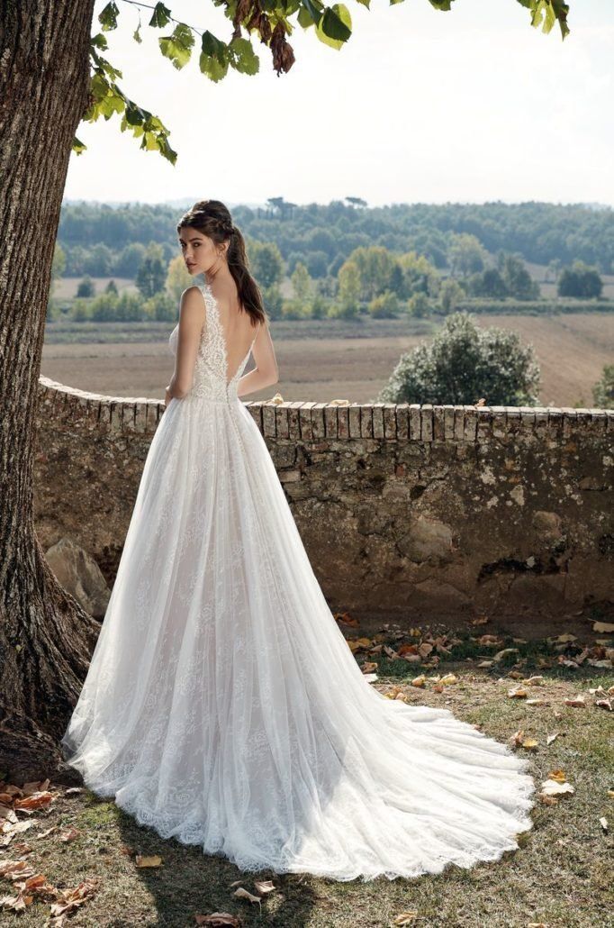 Eine Frau in einem Brautkleid steht neben einem Baum.