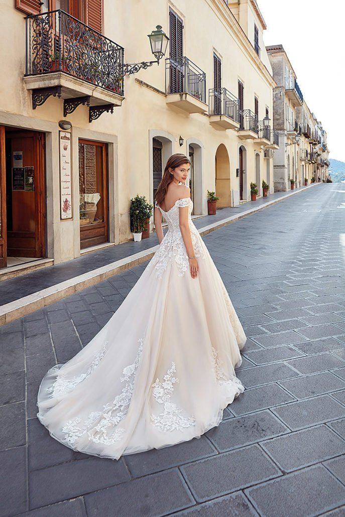 Eine Frau in einem Brautkleid steht auf einem Bürgersteig vor einem Gebäude.