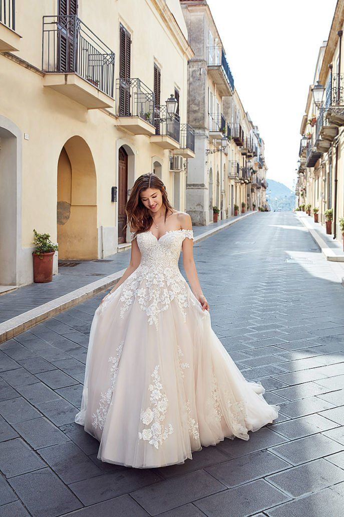 Eine Frau in einem Brautkleid geht eine Straße entlang.