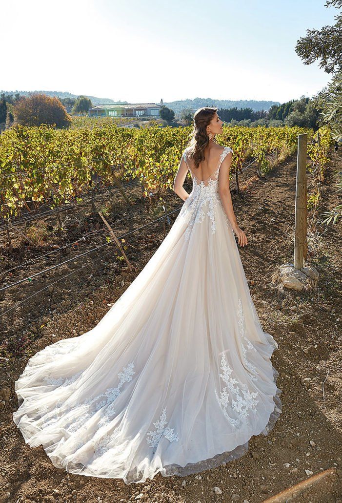 Eine Frau in einem Brautkleid steht in einem Weinberg.