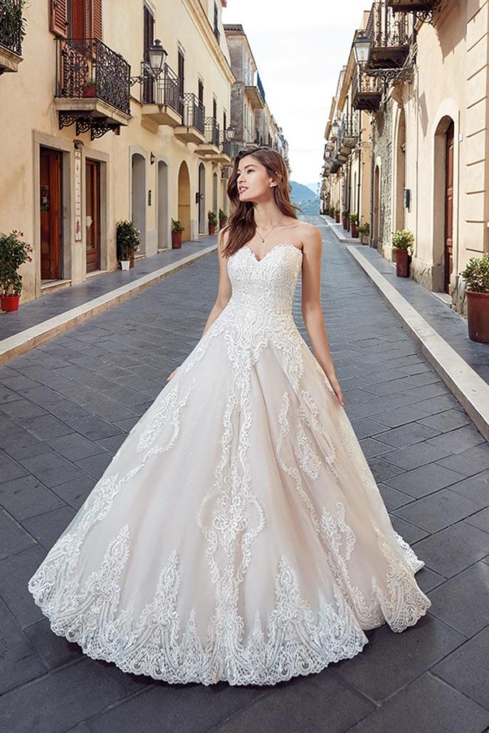 Eine Frau in einem Brautkleid geht eine Straße entlang.