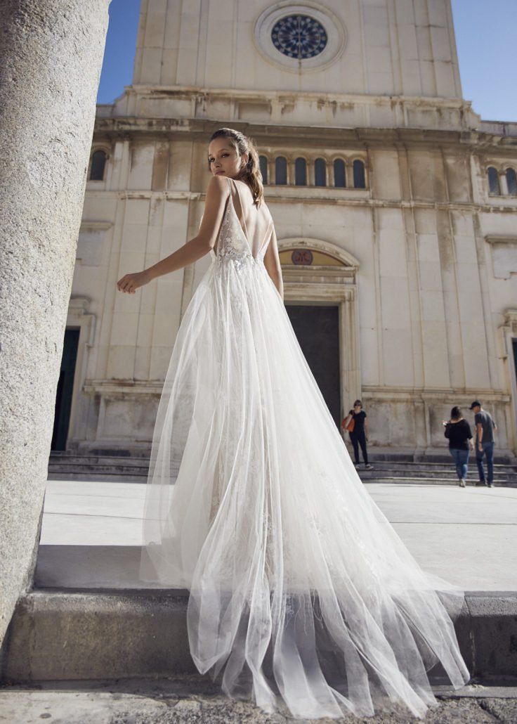 Eine Frau in einem Brautkleid steht vor einem Gebäude.