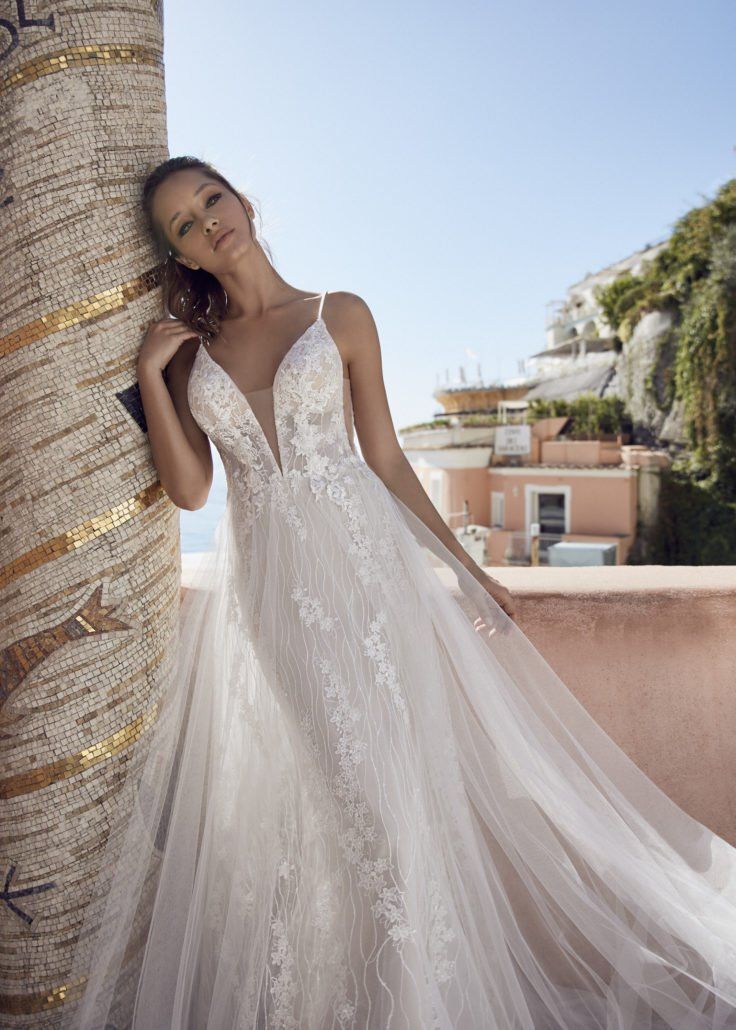 Eine Frau in einem Brautkleid lehnt an einem Baum.