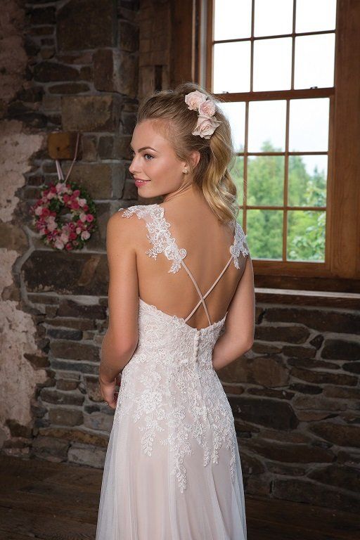 Eine Frau in einem Brautkleid steht vor einem Fenster.