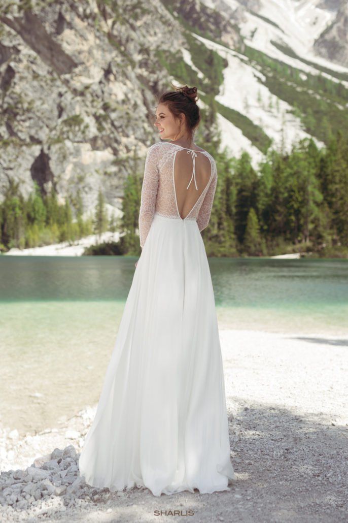 Eine Frau in einem Brautkleid steht vor einem See.