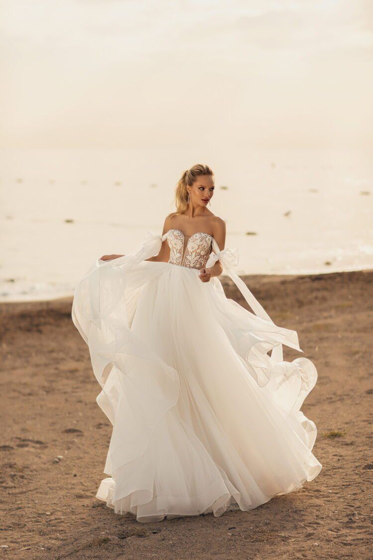 Eine Frau in einem Brautkleid steht an einem Strand.