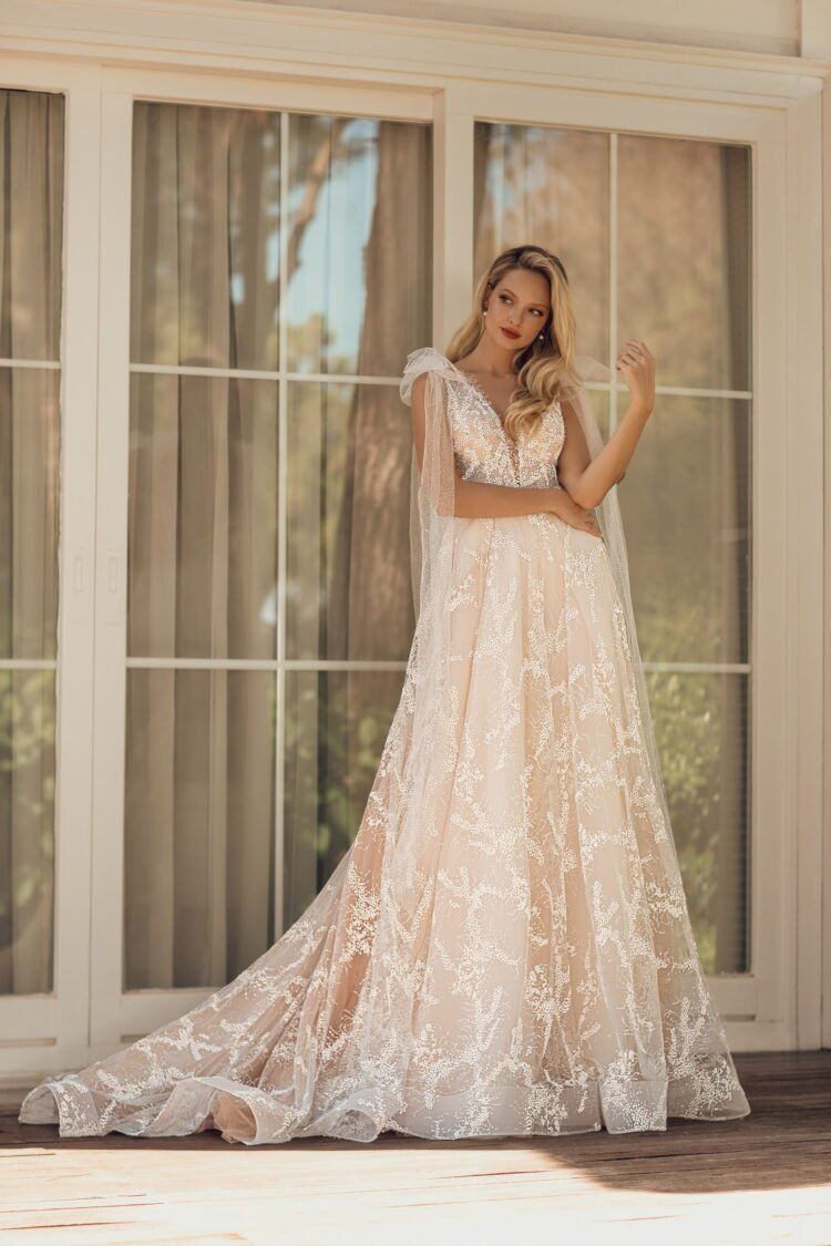 Eine Frau in einem Brautkleid steht vor einem Fenster.