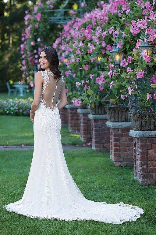 Eine Frau in einem Brautkleid steht vor einer Reihe von Blumen.