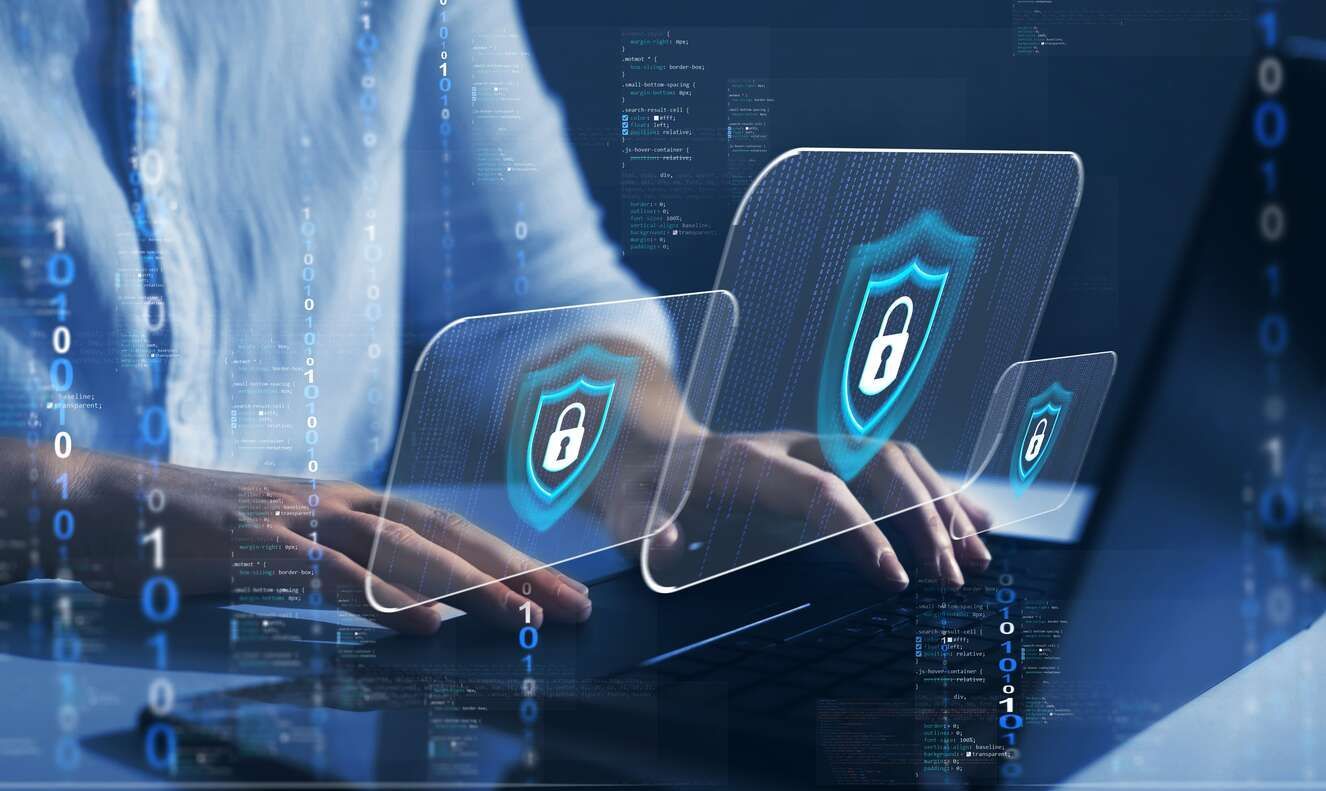 A person uses a laptop while enabling cybersecurity protection.
