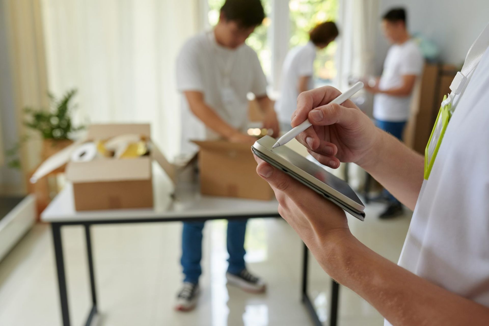 Manager of charity organization taking notes on tablet computer when volunteers packing boxes 