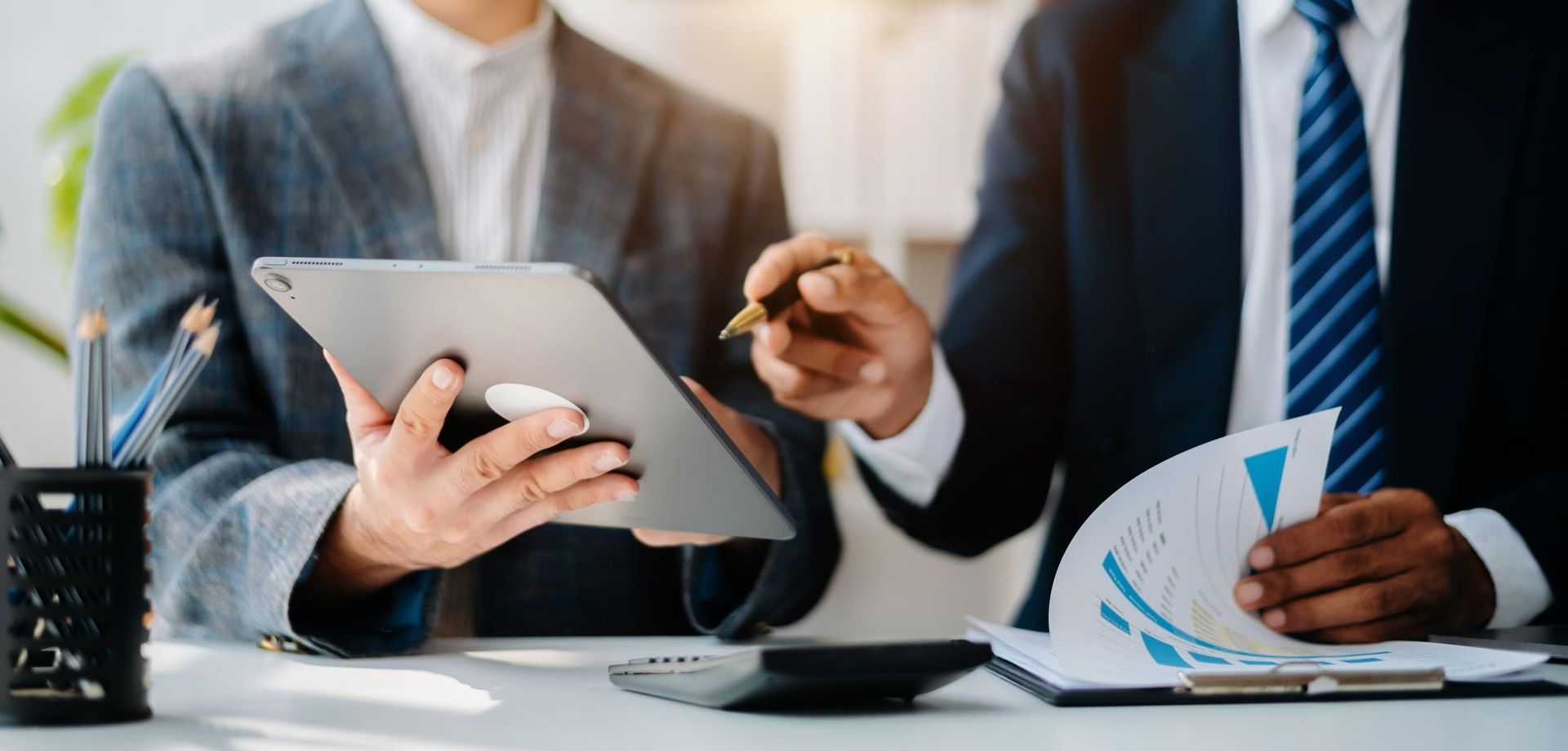 Businessman and team analyzing financial statement with smartphone, laptop, and tablet