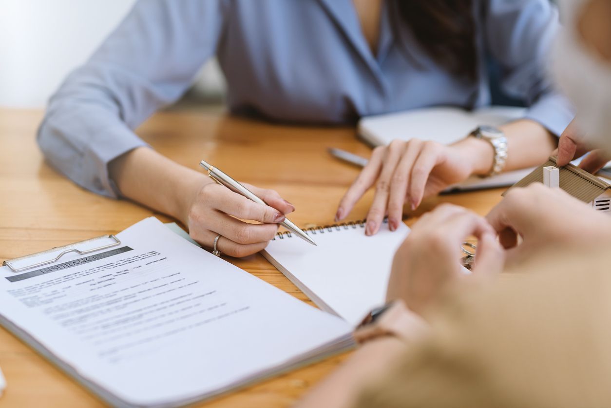 A female insurance agent reviews a contract with a customer.