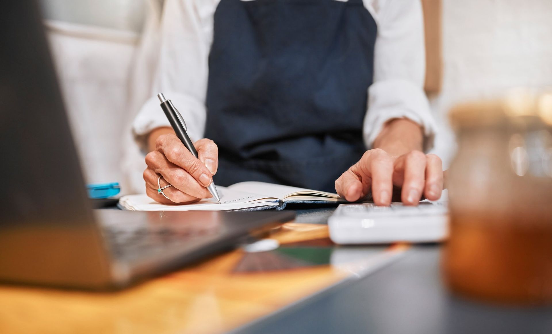 Manager writing a budget for marketing or advertising a small business startup. Notebook, calculator and entrepreneur working on financial data analysis or sales growth goals