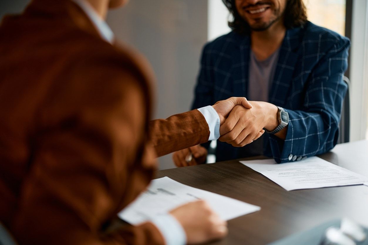 Close up of businesswoman shaking hands with male coworker in office environment.