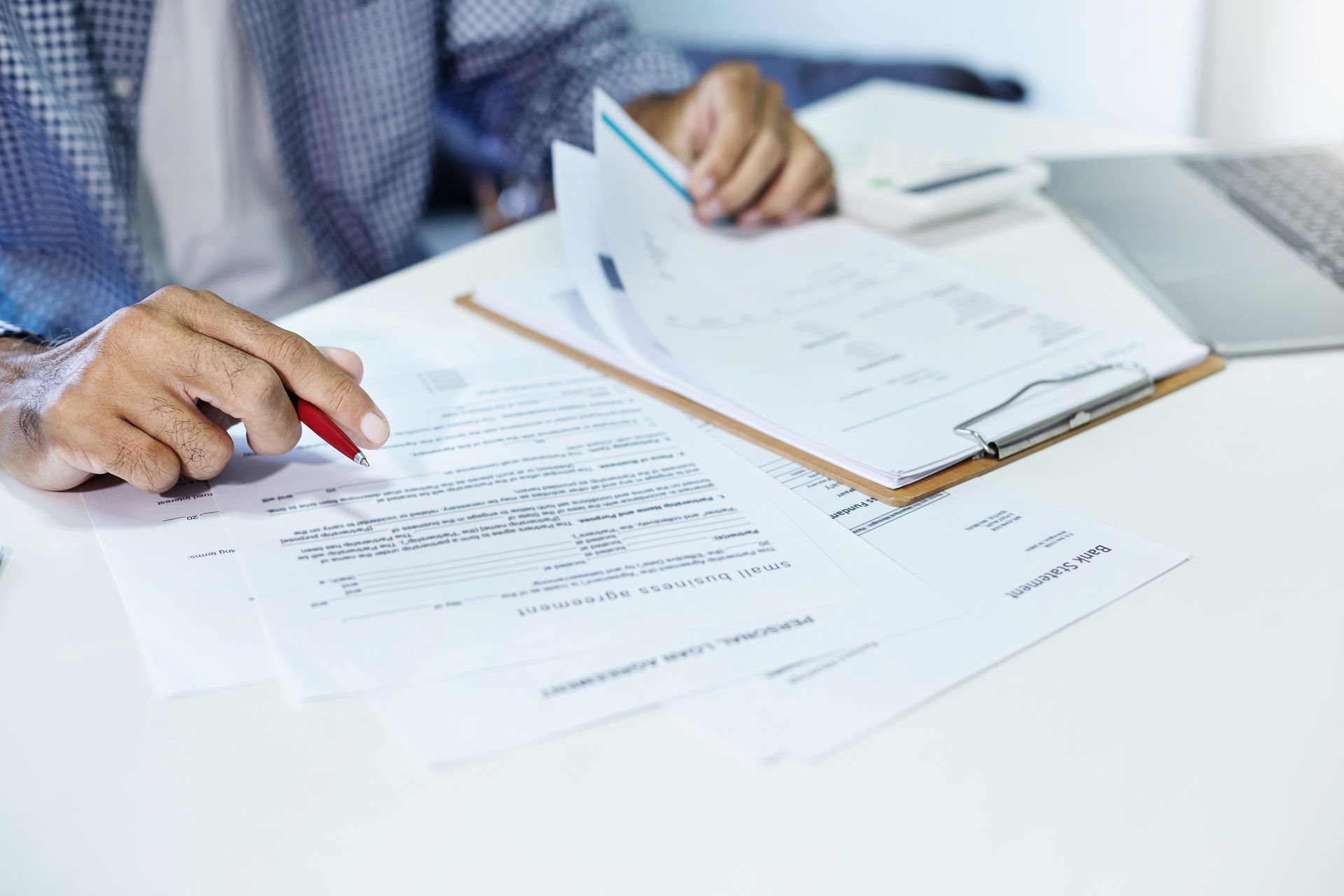 A small business owner is sitting at a table holding a pen, reviewing his company's worker's comp documents