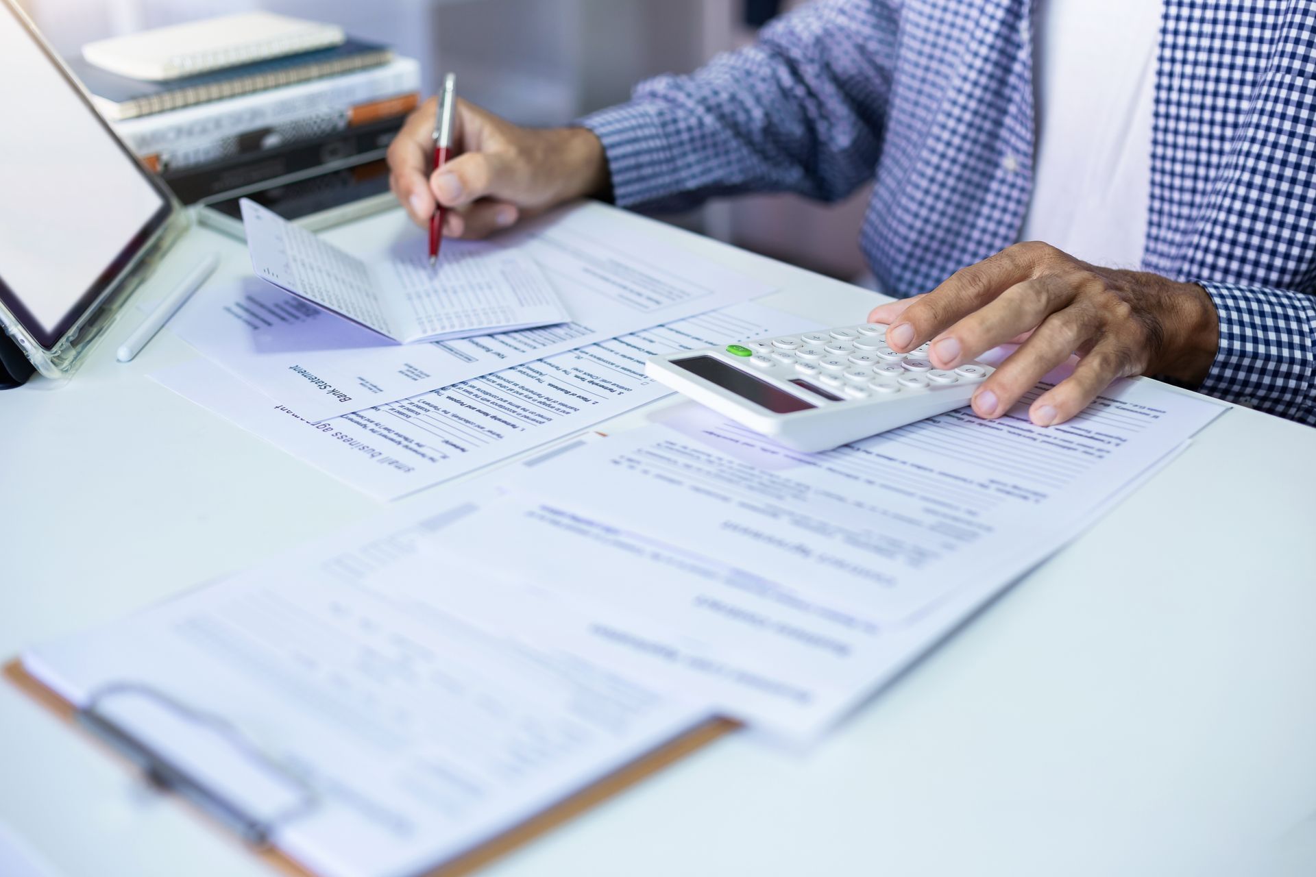 A man is sitting at a desk using a calculator and calculating the cost of the coverage he's gained for his business and employees