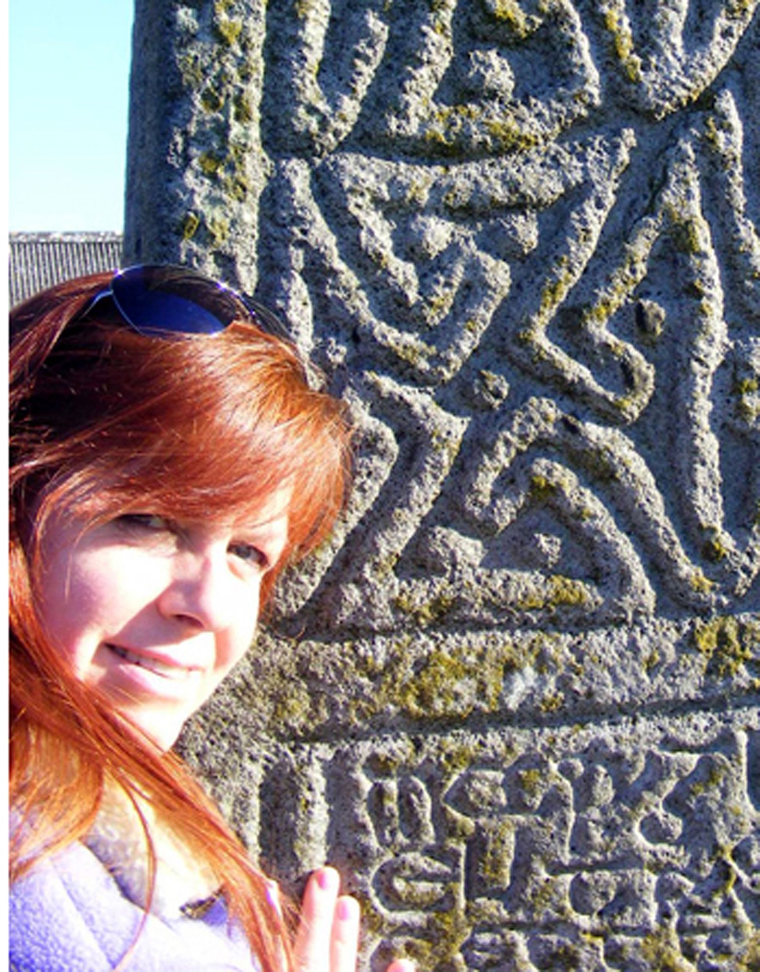 Photo of Lynn Parr, artist, in front of Celtic stone cross