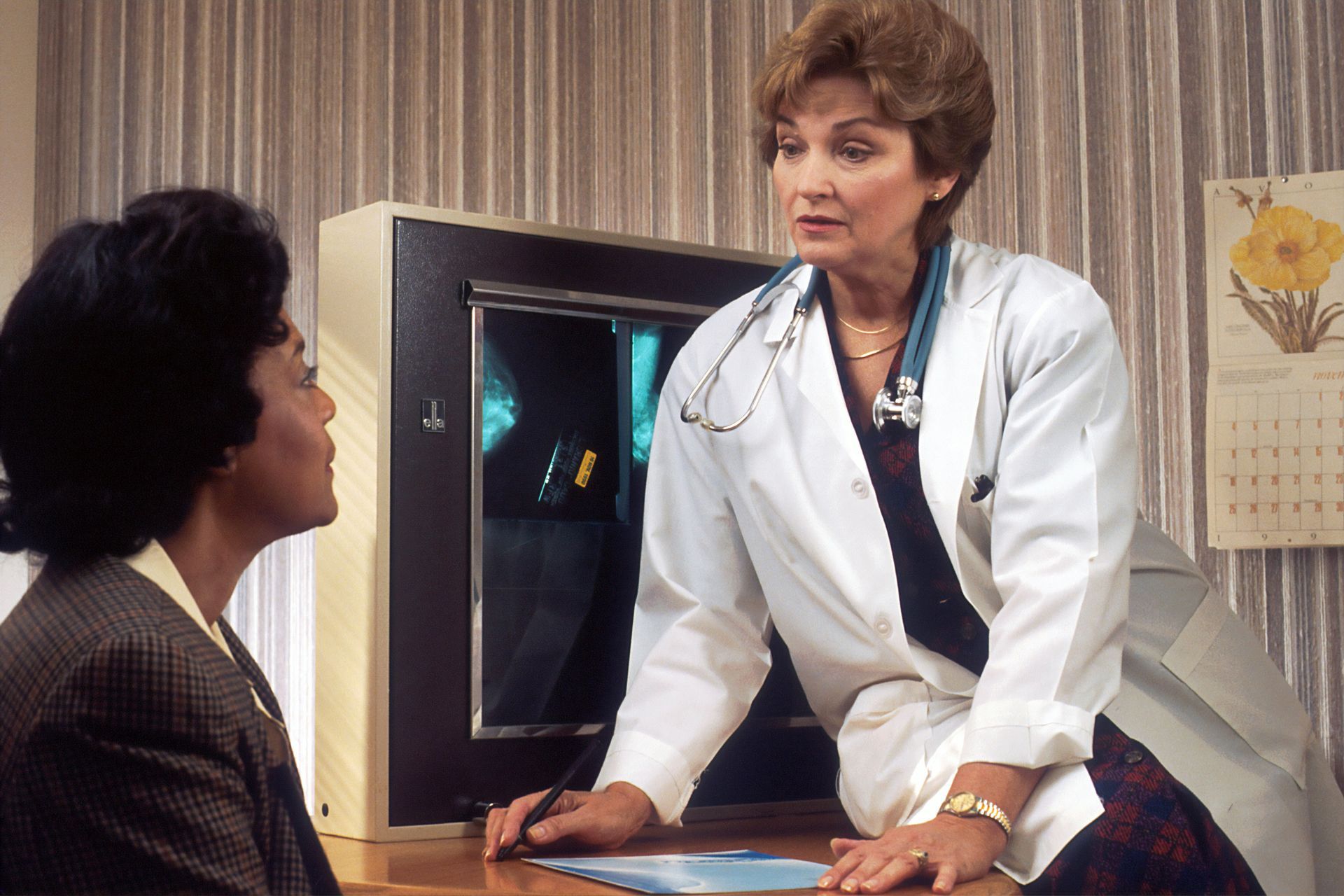 A doctor is talking to a patient in front of an x-ray machine