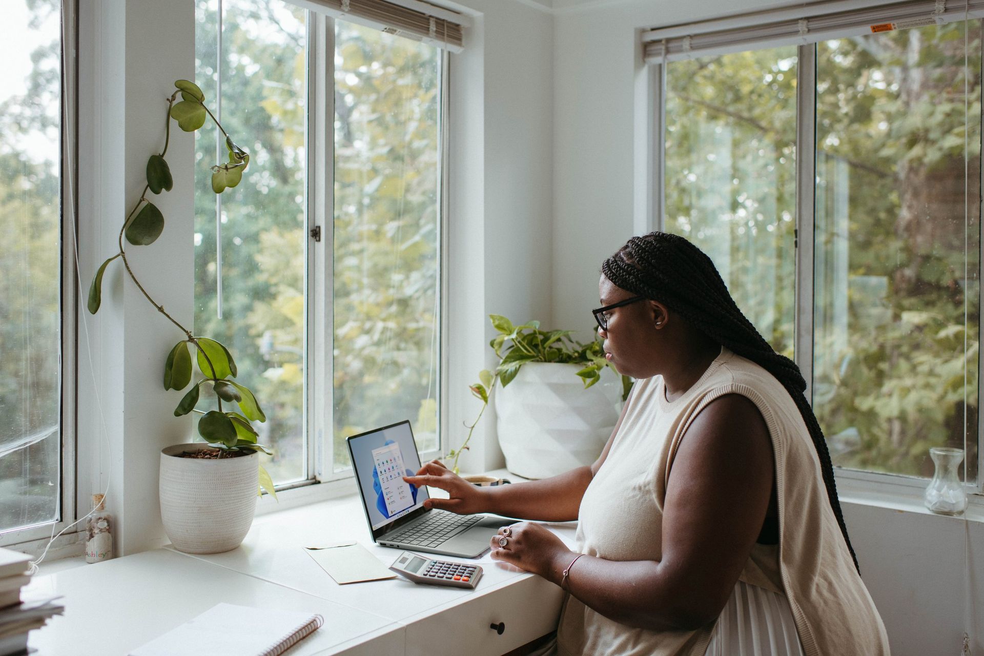 A woman is sitting at a desk using a laptop computer.