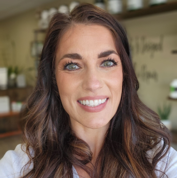 A woman in a leopard print shirt is smiling in front of a tree.