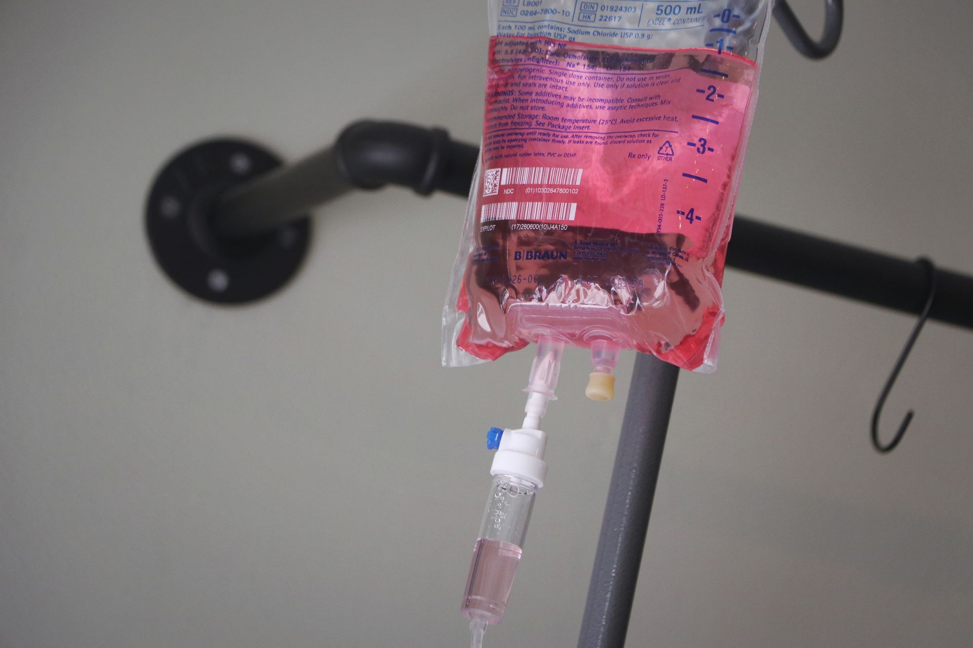 A bag of red liquid is hanging from a hook.