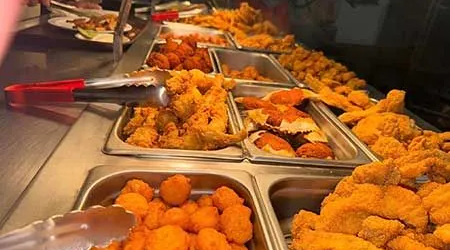 A buffet line filled with lots of fried food and tongs.