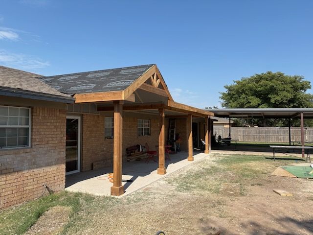 Remodeled Porch o  a brick house with  wooden posts, and a yard under a clear blue sky.