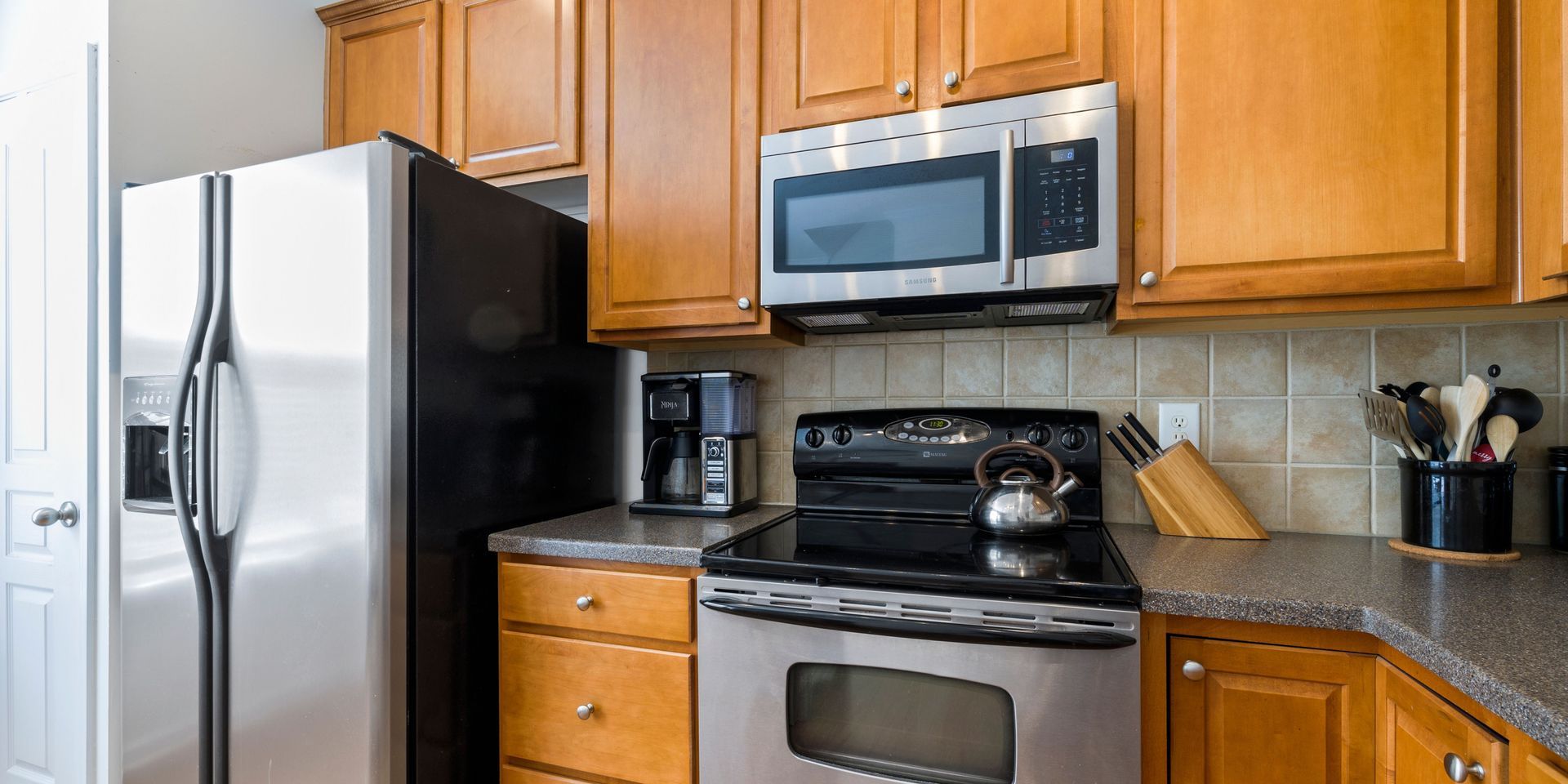A kitchen with stainless steel appliances , wooden cabinets , a refrigerator , stove and microwave.