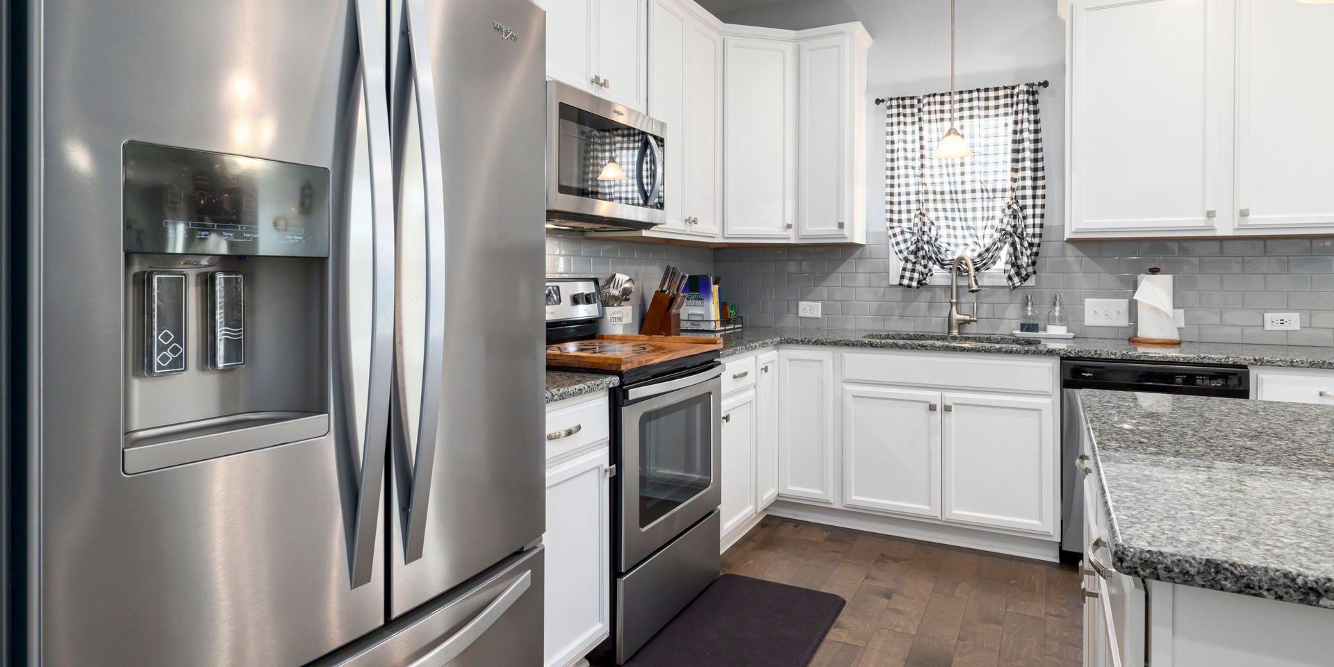 A kitchen with stainless steel appliances and white cabinets.
