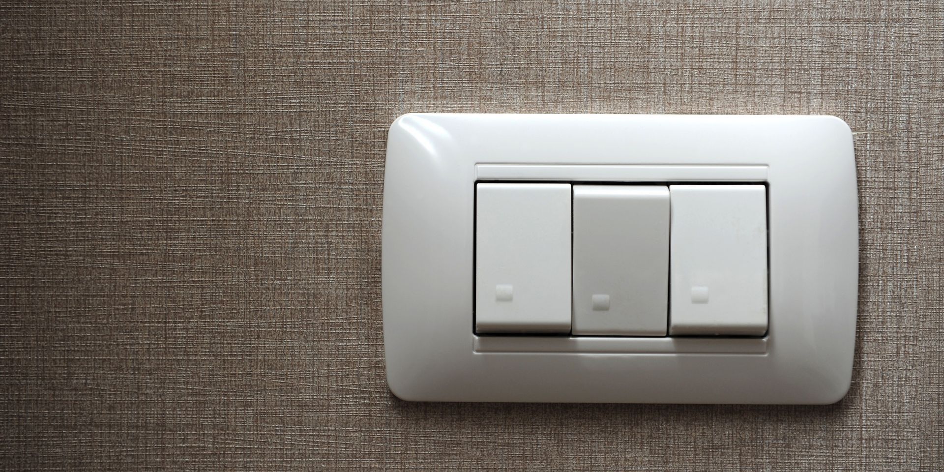 A close up of a white light switch on a wall.