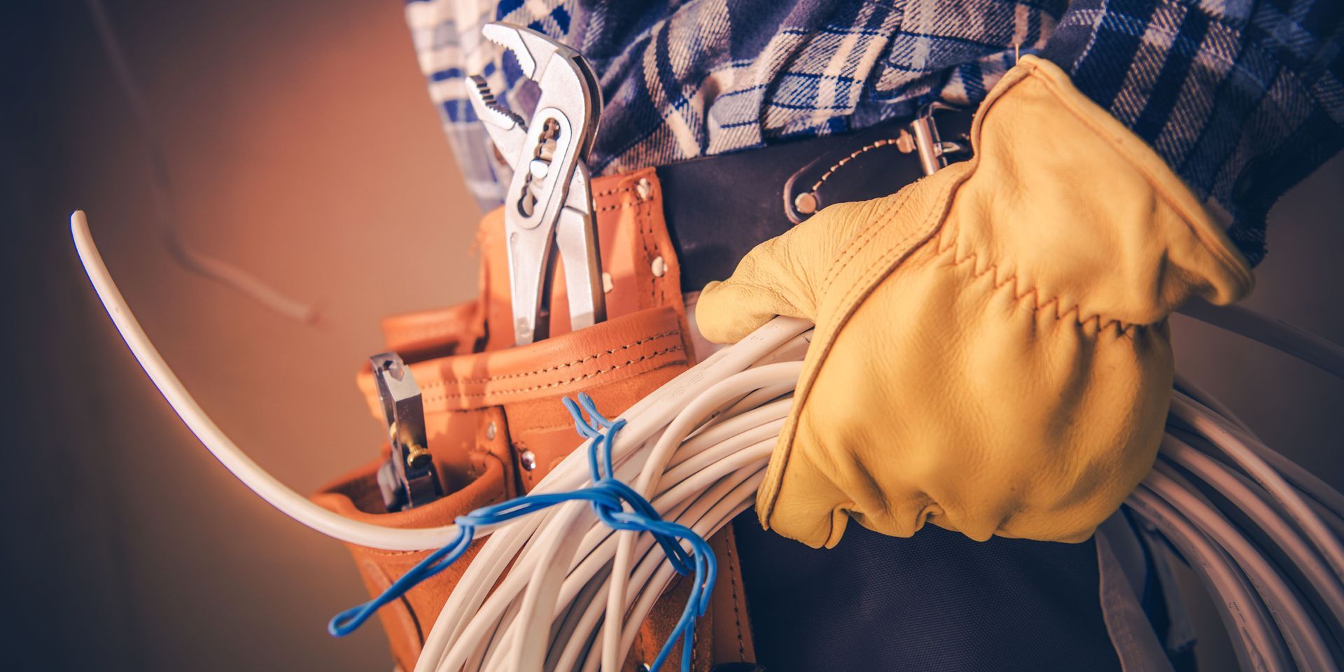 A man is holding a roll of wires and a tool belt.