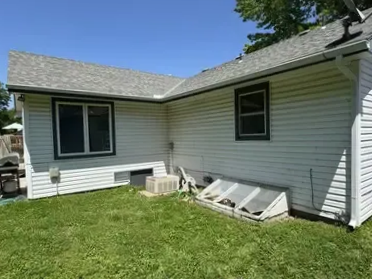 white house with bright green lawn and gutters under shingled roof