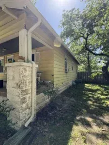 Yellow house exterior with white trim, porch, and a green yard.