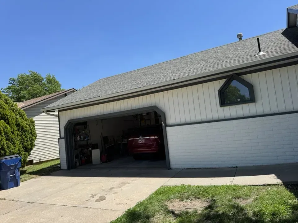 White Derby KS home with new gutters and open garage door on a sunny day