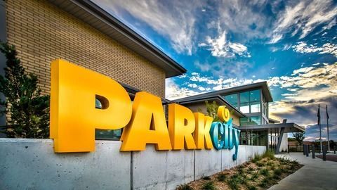Yellow house with white gutters and shutters, viewed from angled sidewalk on a sunny day.