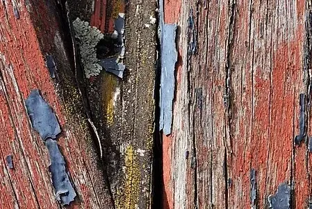 Weathered wood with peeling red and blue paint.