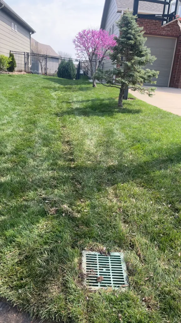 Brown seamless gutter and downspout matching a wooden house with trees in the background.