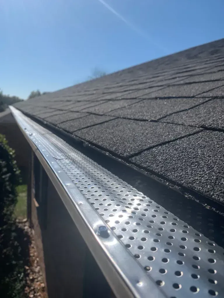 Gutter guard shown on the entire length of a gutter on a house with shingles