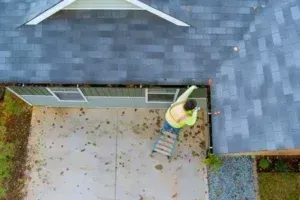 Worker cleaning clogged gutter in wichita