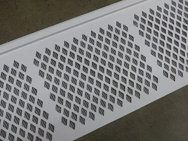 Close up of White metal gutter guards with diamond-shaped perforations