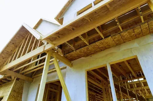 Wooden house under construction; exposed framing, unfinished exterior.