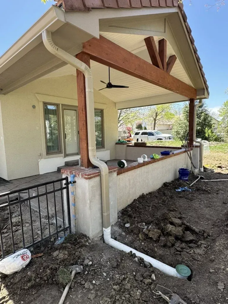 Exterior view of a house with a porch. White gutters, tan stucco, and exposed wood beams.