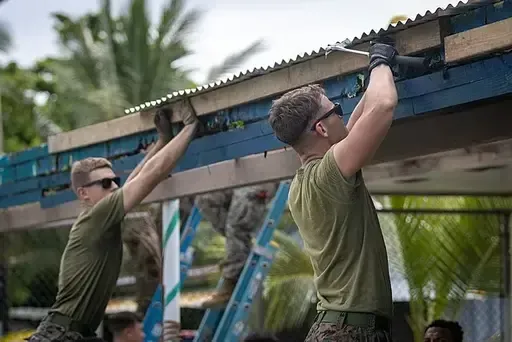 Owner of Wichita Gutters in green shirt with crewmember assisting with building fascia on building