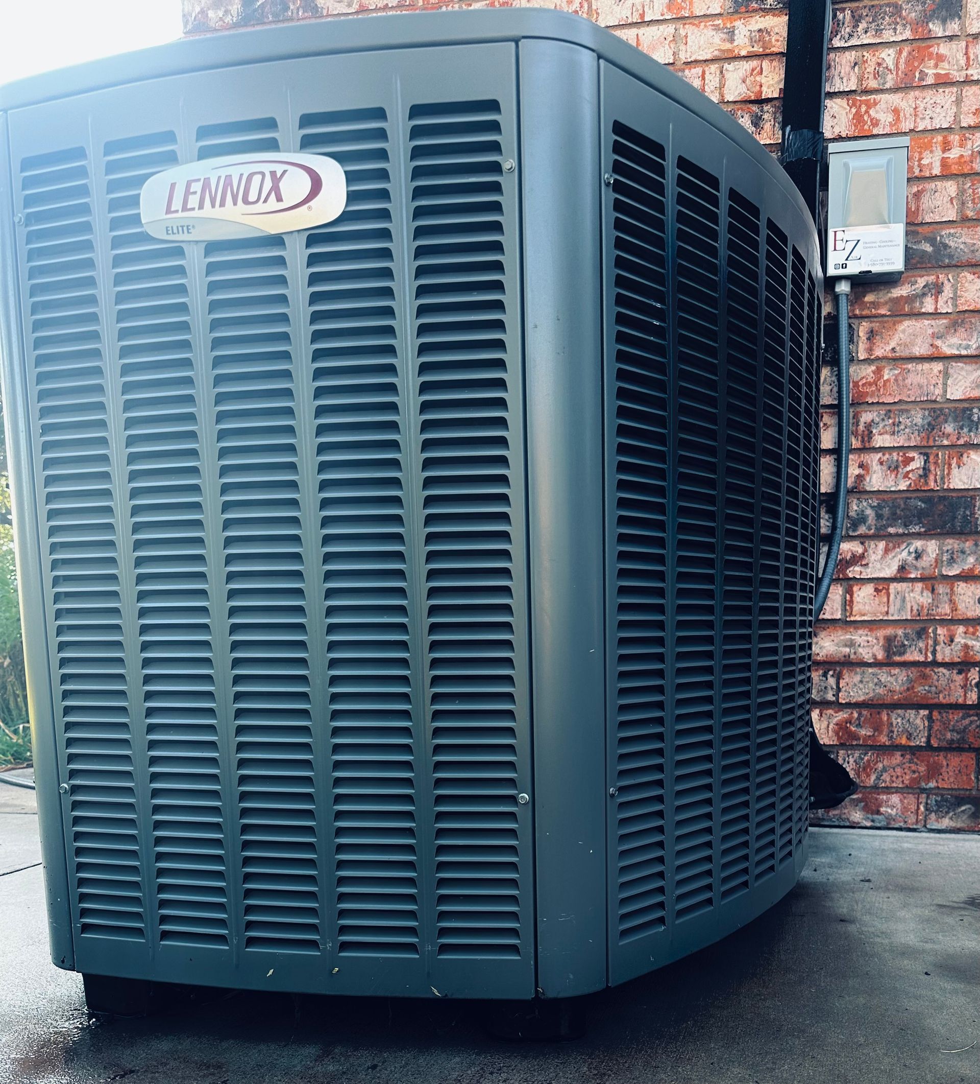A lennox air conditioner is sitting outside of a brick building.