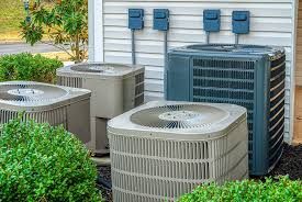 Three air conditioners are sitting outside of a house.