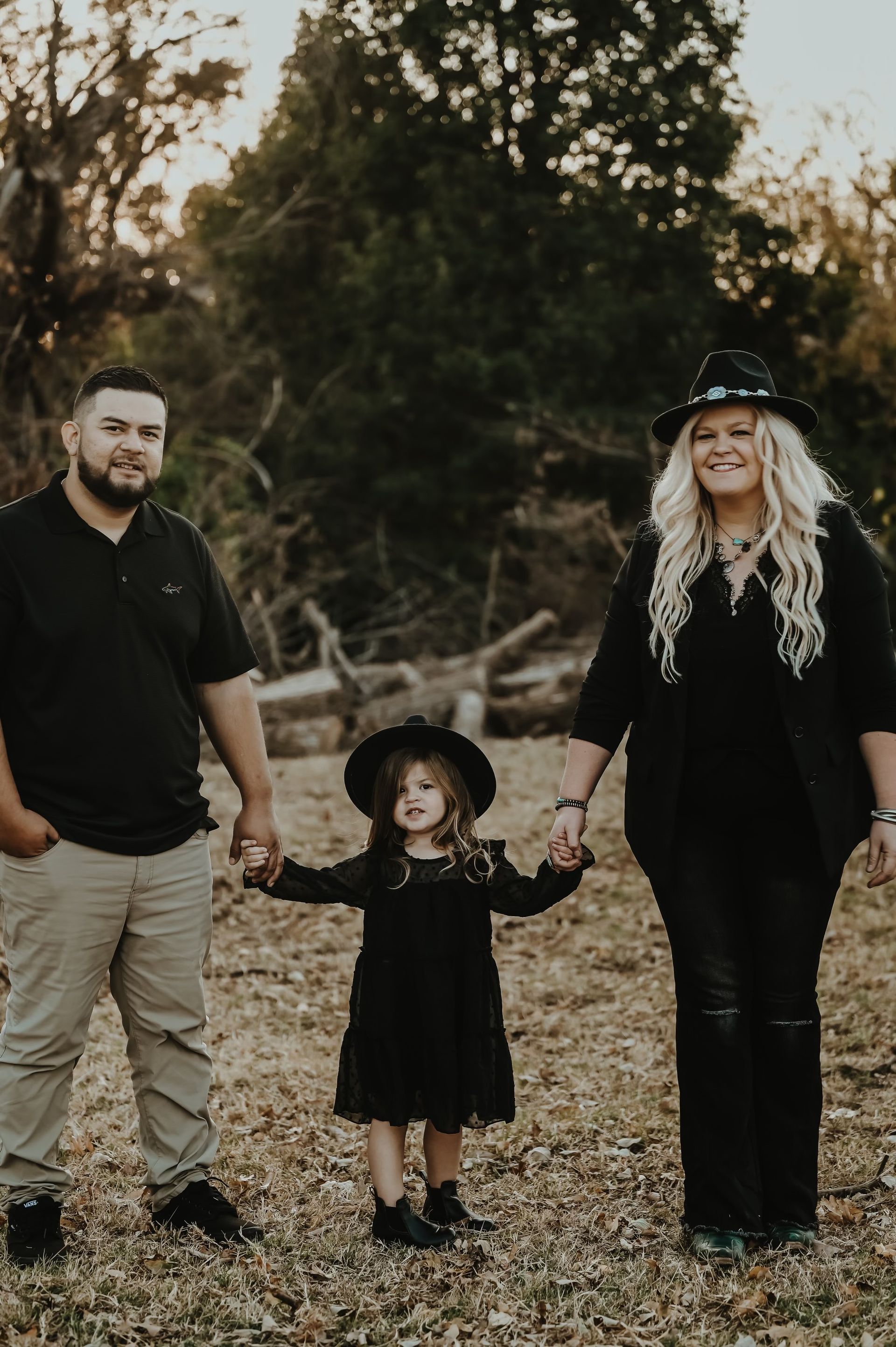 A family is posing for a picture in a field holding hands.